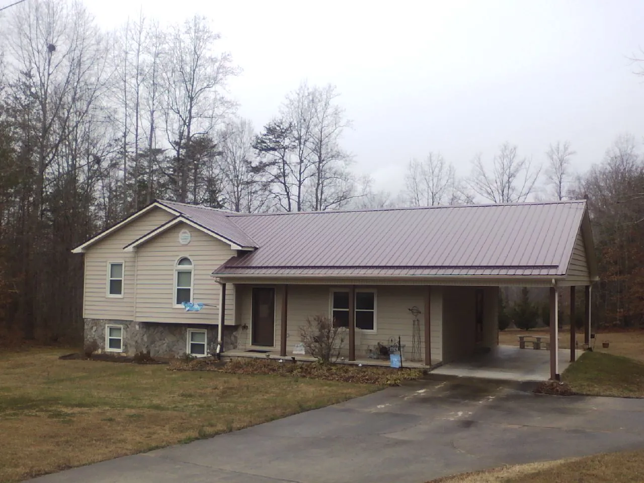 Burgundy metal roof on a tan split level home with an attached carport in Cashton