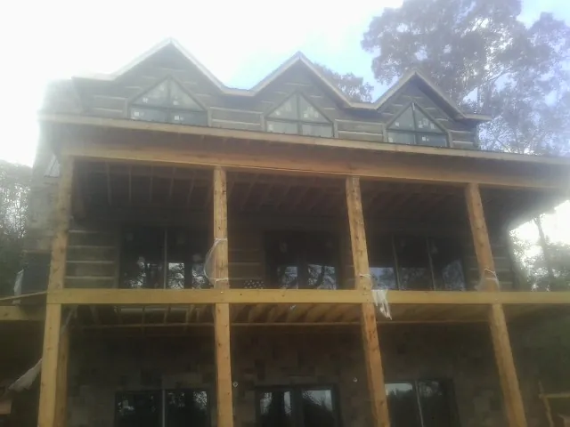 Dormers and porch framing on a large log home under construction — Roof Coating work by our crew in Cashton