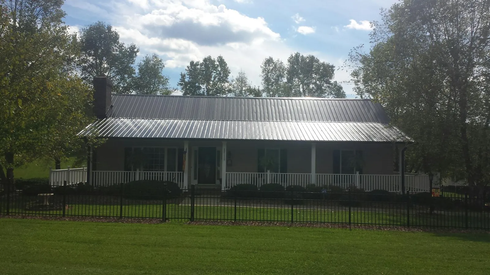 Gray metal roof on a brick ranch with a full width front porch — Gutter Guard Installation work by our crew in Cashton