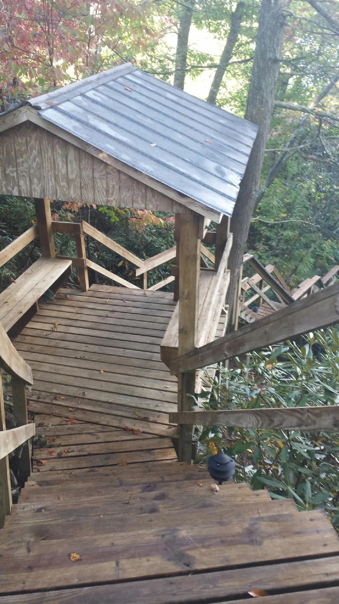 Metal roofed shelter over wooden steps on a wooded walkway — Skylight Repair & Installation work by our crew in Cashton