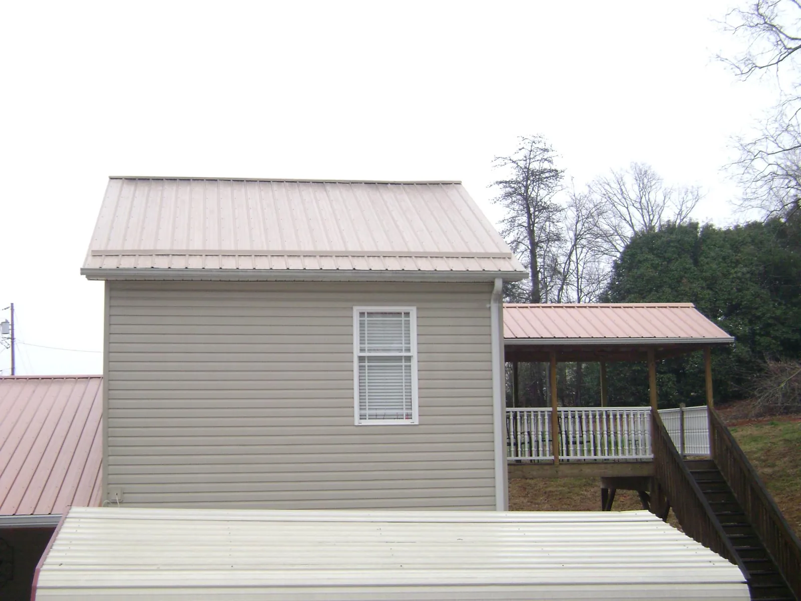 Tan metal roofs on a two story addition and attached porch, from a Roof Replacement job in Cashton