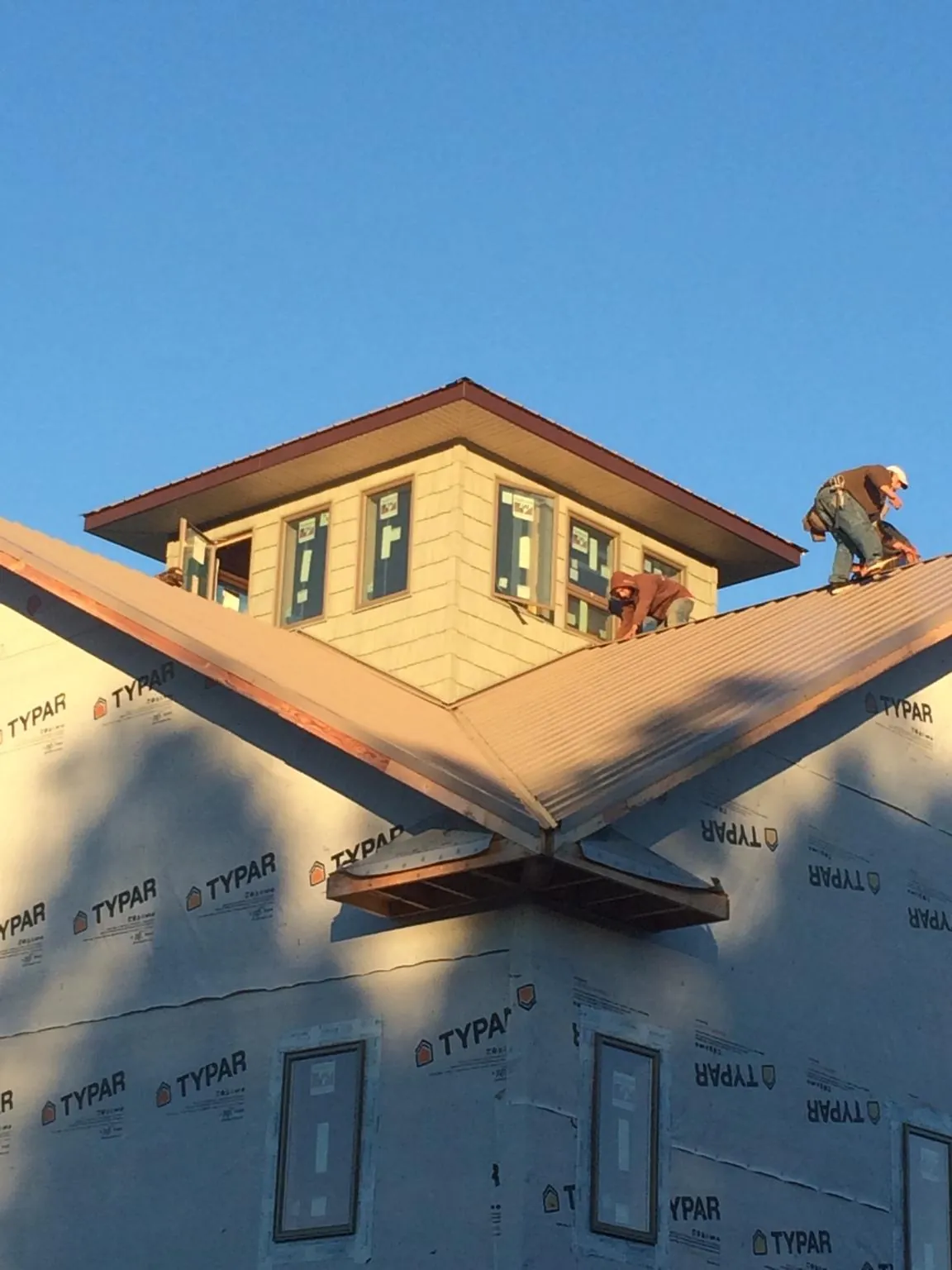 Roofers working around a rooftop cupola on a new metal roof at sunset — Roof Waterproofing in Cashton by Roofing Brothers